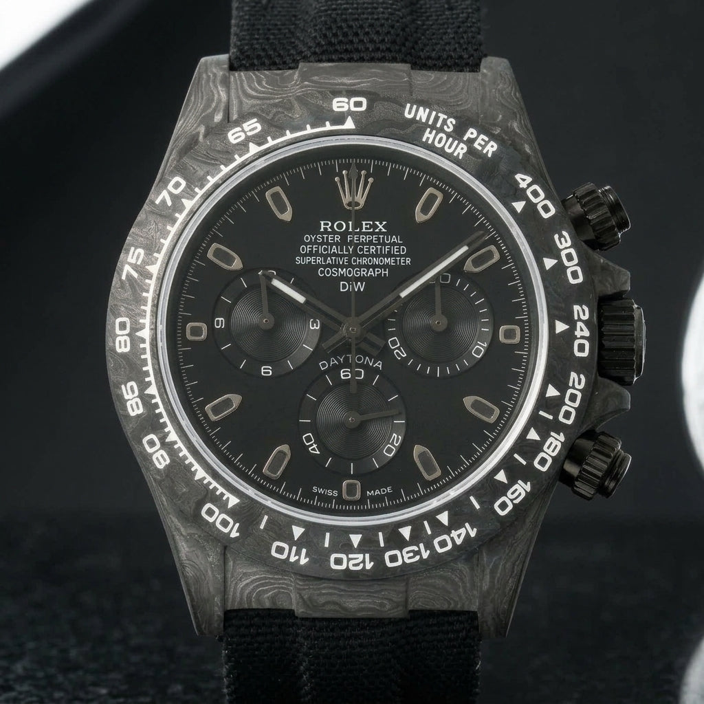 All-black forged-carbon chronograph on a black woven strap, worn under a cuff