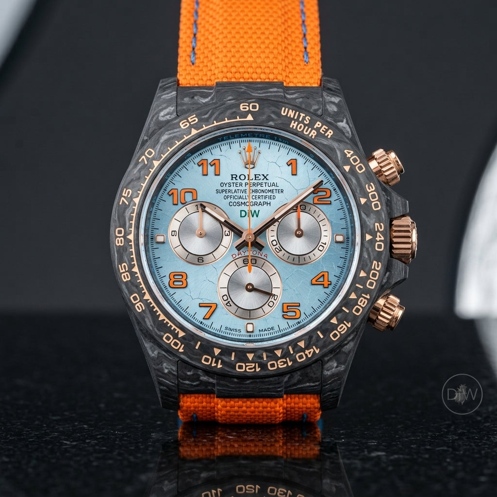 Forged-carbon chronograph on an orange woven strap, worn under a cuff