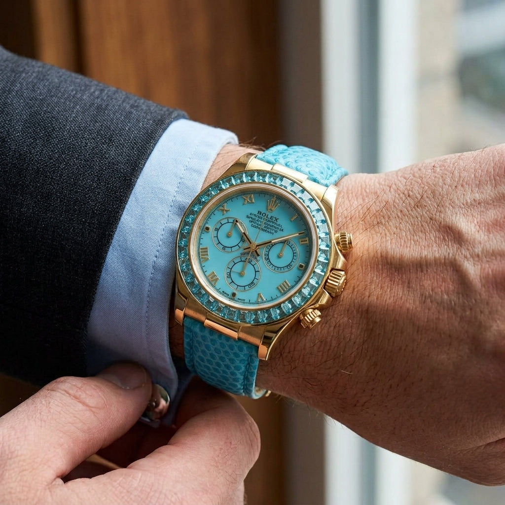 Gold-tone chronograph with a turquoise dial and an aqua-blue stone bezel on the wrist as a shirt cuff is fastened