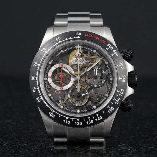 Steel skeleton chronograph with a matte black bezel and black pushers, upright on polished black granite