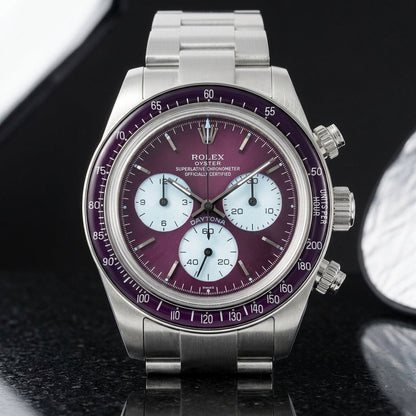 Steel chronograph with a plum-purple dial, ice-blue counters and a plum bezel, upright on polished black granite