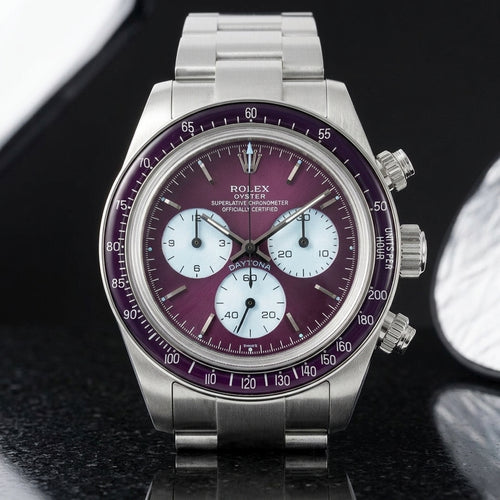 Steel chronograph with a plum-purple dial, ice-blue counters and a plum bezel, upright on polished black granite