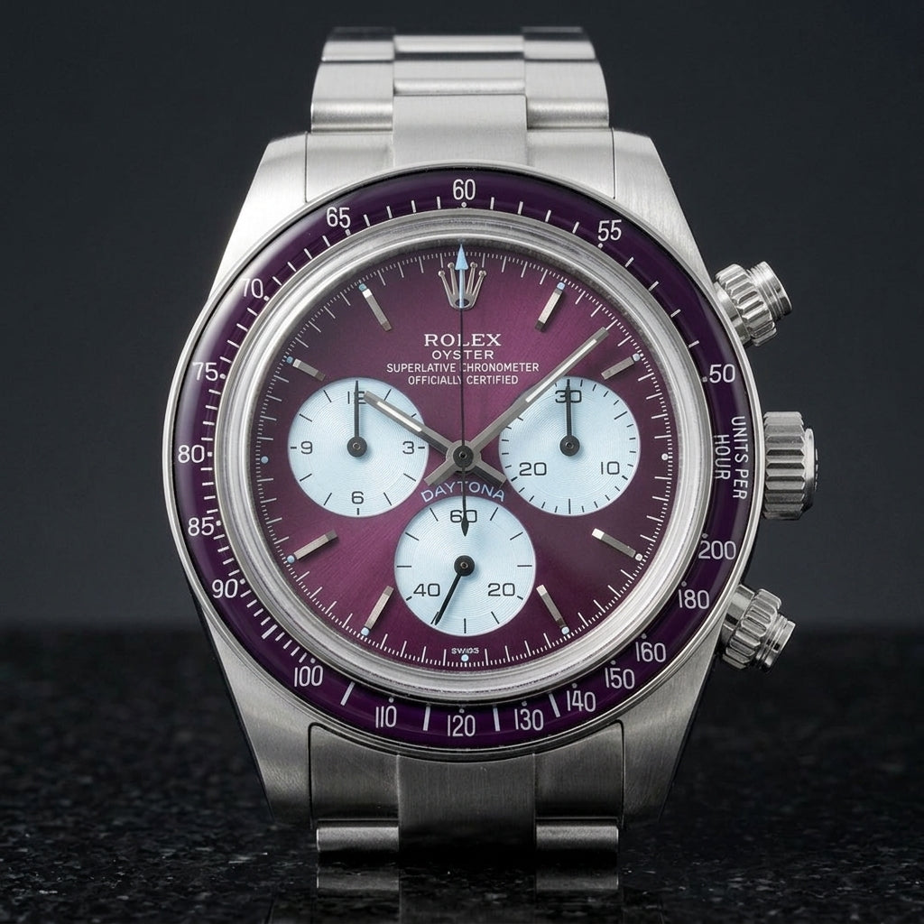 Steel chronograph with a plum dial on its steel bracelet, worn on the wrist below a dark suit cuff