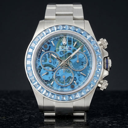 Steel skeleton chronograph with a sky-blue stone bezel and a sky-blue skeleton dial, upright on polished black granite