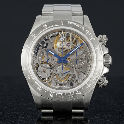 Steel skeleton chronograph with a grey open-worked dial and blue hands, upright on polished black granite