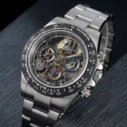 Steel skeleton chronograph at a three-quarter angle on dark slate, the carbon bezel beside the polished steel pushers and crown
