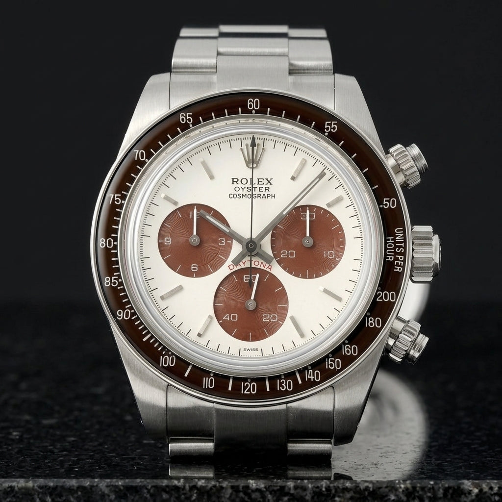 Steel chronograph with a white dial and brown counters on its steel bracelet, worn on the wrist below a dark suit cuff