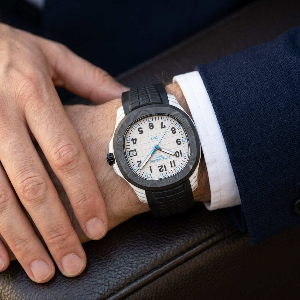 White carbon watch with a black bezel on a black rubber strap, worn on the wrist below a navy suit cuff