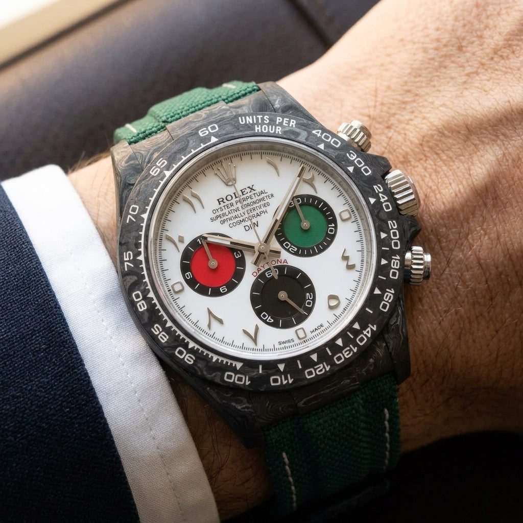 Forged-carbon chronograph on a green woven strap with white stitching, worn under a cuff