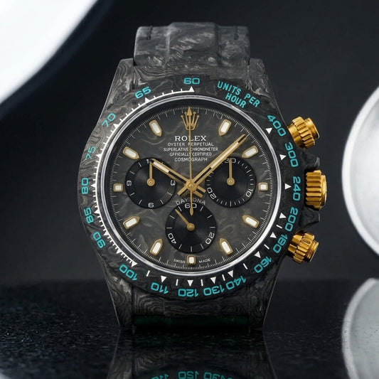 Forged-carbon chronograph with a carbon dial and gold fittings on pale stone