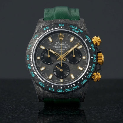 Forged-carbon chronograph on a dark green leather strap, worn under a cuff