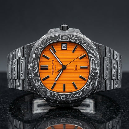 Forged carbon sports watch with a bright orange dial and polished black markers, upright on polished black granite