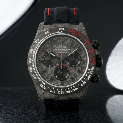 Forged-carbon chronograph with a marbled carbon dial and red seconds hand on dark stone