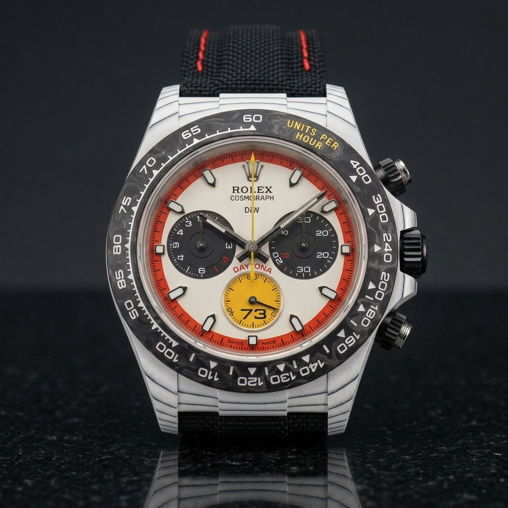 White carbon chronograph on its black canvas strap with red stitching, worn on the wrist below a navy suit cuff