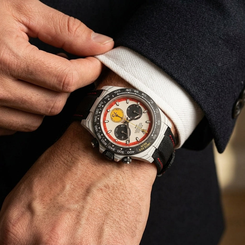 White forged carbon chronograph with a red-ringed cream dial and a yellow 73 counter on the wrist as a shirt cuff is fastened
