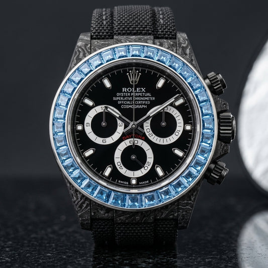 Black forged-carbon chronograph with a sky-blue stone bezel and a black dial, upright on polished black granite
