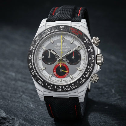 White forged carbon chronograph at a three-quarter angle on dark slate, fine dark layer lines along its flank