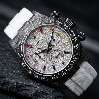 Black forged carbon chronograph at a three-quarter angle on dark slate, its black crown and pushers against the marbled carbon flank