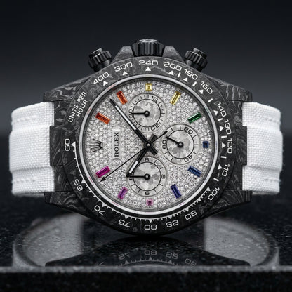 Carbon chronograph with a white pavé dial on its white woven strap, worn on the wrist below a navy suit cuff and white shirt