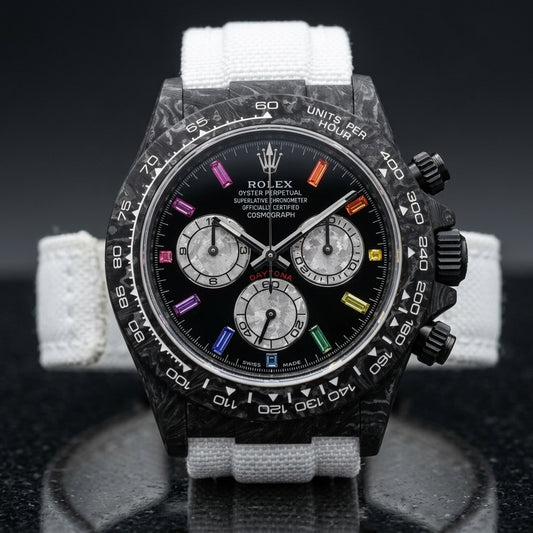 Black forged carbon chronograph with a carbon tachymeter bezel and a black dial with rainbow stone markers, upright on polished black granite
