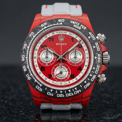 Red forged carbon chronograph with a black carbon bezel, a red telemetre dial and three silver counters, upright on polished black granite