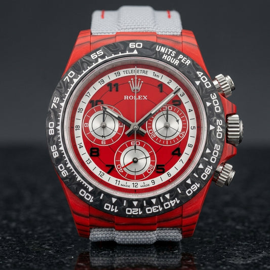 Red forged carbon chronograph with a black carbon bezel, a red telemetre dial and three silver counters, upright on polished black granite