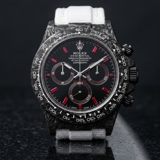 Black forged carbon chronograph with red baguette stone markers on a black dial and a white tachymeter scale, upright on polished black granite
