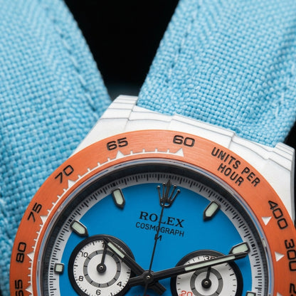Macro of the sky-blue dial inside the white minute-track ring, two white counters ringed in black and an orange counter at six