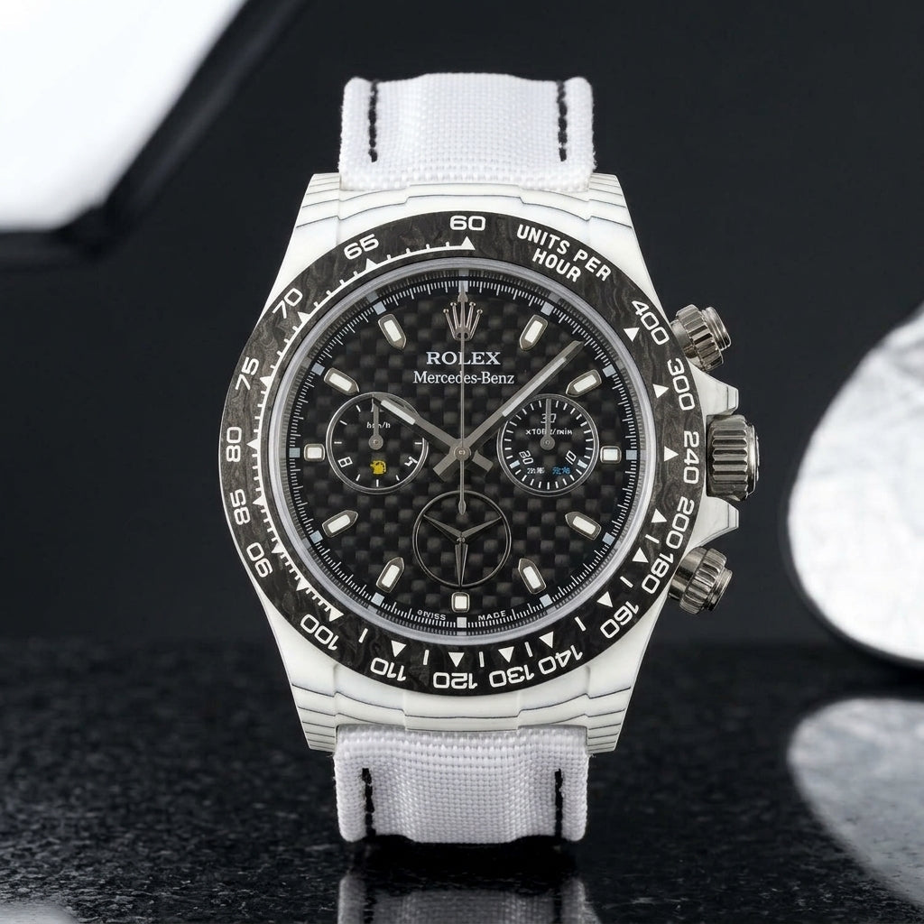 White carbon chronograph on its white woven canvas strap, worn on the wrist below a navy suit cuff