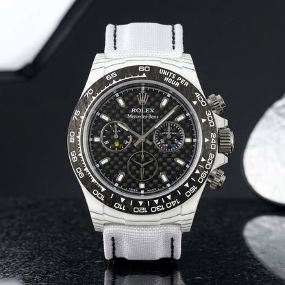 White carbon chronograph on its white woven canvas strap, worn on the wrist below a navy suit cuff