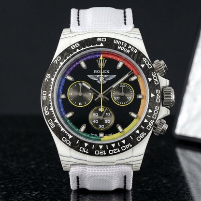 White carbon rainbow-ring chronograph on its white woven canvas strap, worn on the wrist below a navy suit cuff