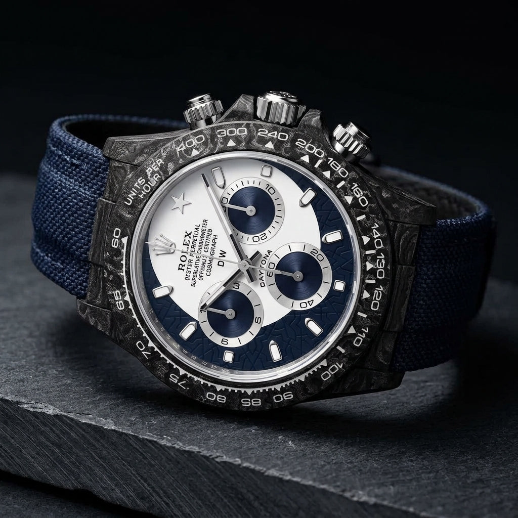 Forged-carbon chronograph at a three-quarter angle, navy sun-brushed counters and navy strap visible