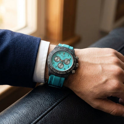 Forged-carbon chronograph on a turquoise woven strap, worn under a cuff