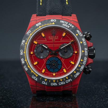 Red forged-carbon chronograph on a black woven strap with yellow stitching, worn under a cuff