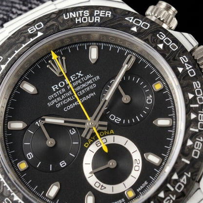 Macro of the black dial with yellow square markers, a yellow chronograph hand and a silver-white ring round the six o'clock counter inside the forged-carbon bezel