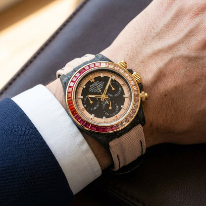 Forged carbon chronograph on a blush fabric strap worn under a suit cuff