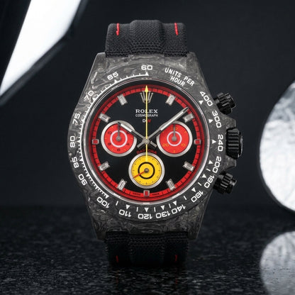 Carbon racing chronograph on a black fabric strap worn under a suit cuff