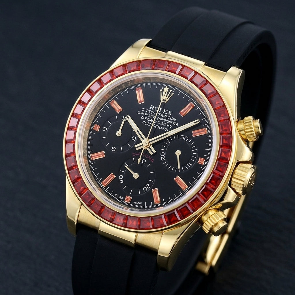 Gold-tone chronograph at a three-quarter angle on dark slate, the fluted crown and pushers beside the ring of red stones