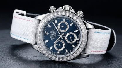 Steel chronograph at a three-quarter angle on dark slate, the fluted crown and pushers beside the clear stone bezel