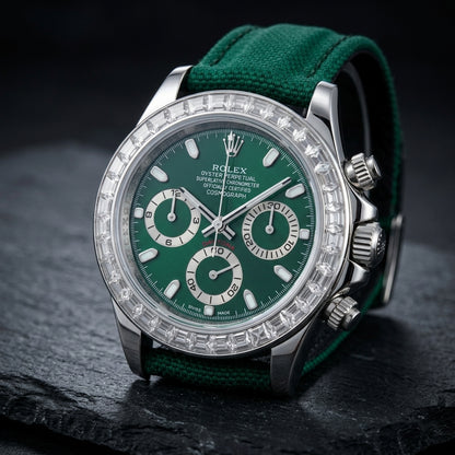Steel chronograph at a three-quarter angle on dark slate, the clear baguette stones and the fluted crown and pushers beside the green dial