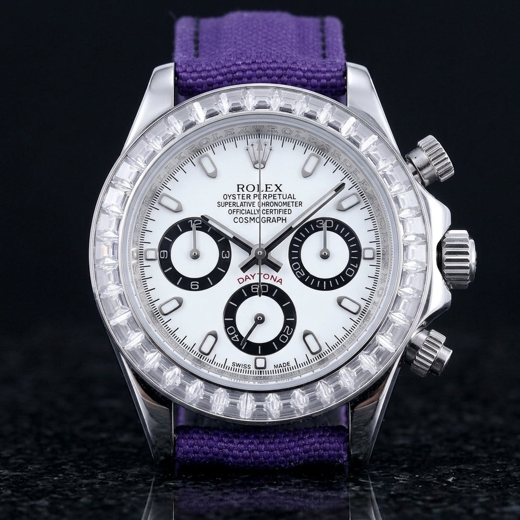 Steel chronograph with a white dial on its purple canvas strap, worn on the wrist below a dark suit cuff