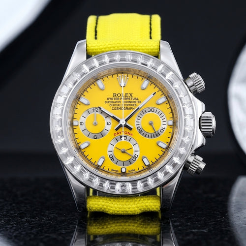 Steel chronograph with a sunflower-yellow dial and a bezel of clear baguette-cut stones, upright on polished black granite