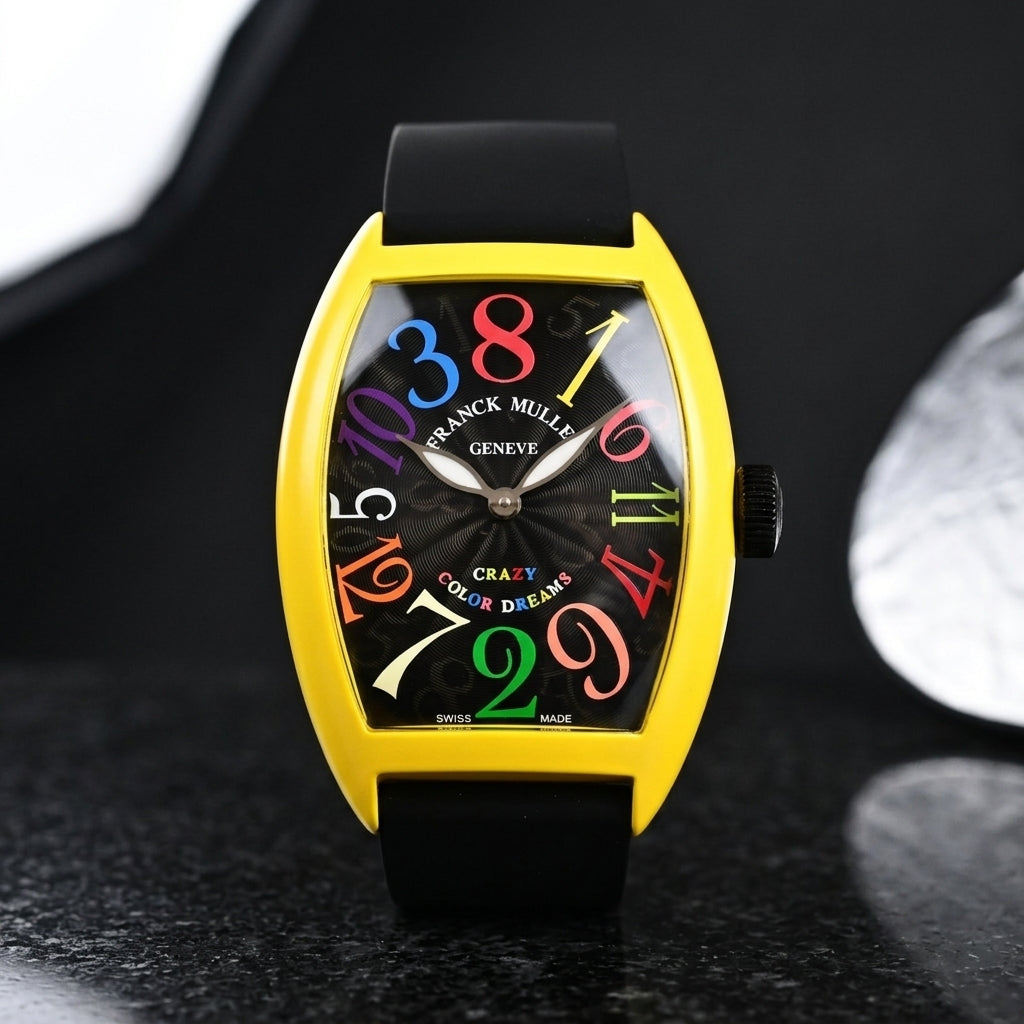 Yellow tonneau watch with a black dial on its black rubber strap, worn on the wrist below a dark suit cuff