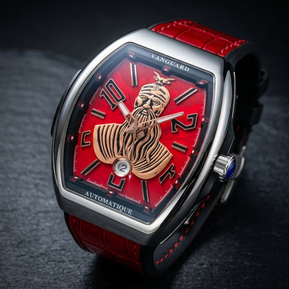 Steel curved tonneau watch at a three-quarter angle on dark slate, the blue-tipped crown beside the black flank band