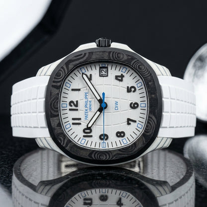 White carbon watch with a black bezel on a white rubber strap, worn on the wrist below a navy suit cuff