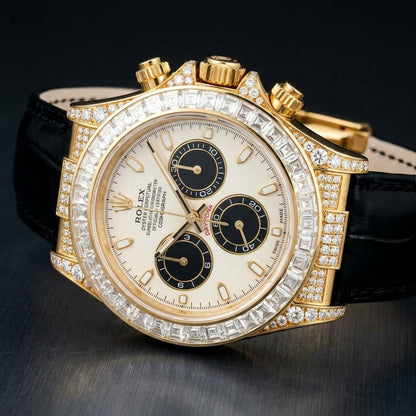 Gold chronograph with a clear baguette bezel and stone-set lugs at a three-quarter angle on dark slate, its black alligator strap curving away