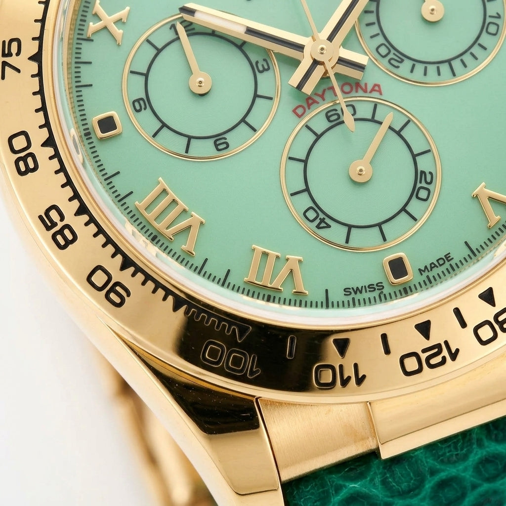 Macro of the pale green satin dial, its gold Roman numerals, three pale green counters ringed in gold and the black tachymeter scale
