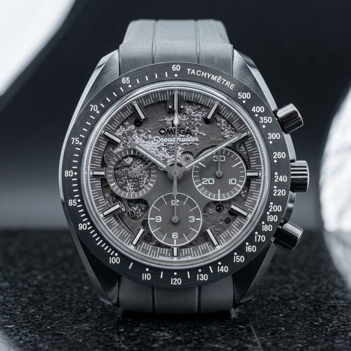 Grey ceramic chronograph with a mid-grey moon relief dial and all-grey hands, standing upright on polished black granite