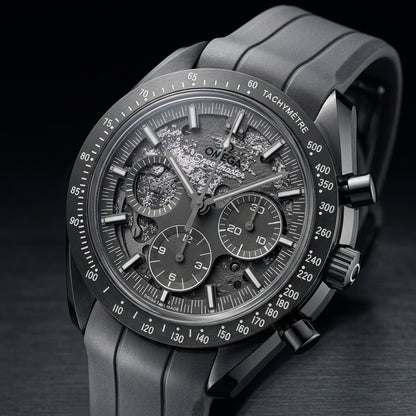 Grey ceramic chronograph at a three-quarter angle on dark slate, with its grey ribbed rubber strap and dark-grey pushers