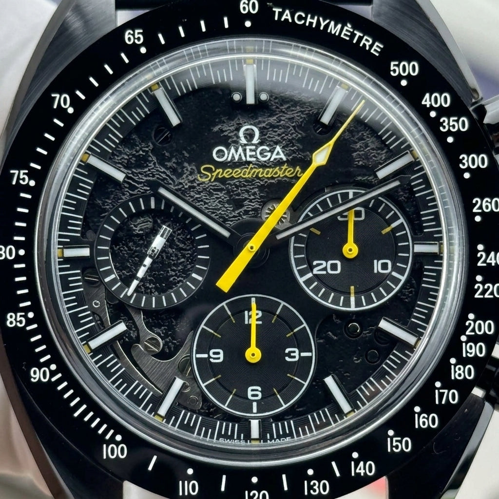 Macro of the black-on-black moon relief dial with the yellow seconds hand, yellow counter hands and the white rocket-shaped small-seconds hand